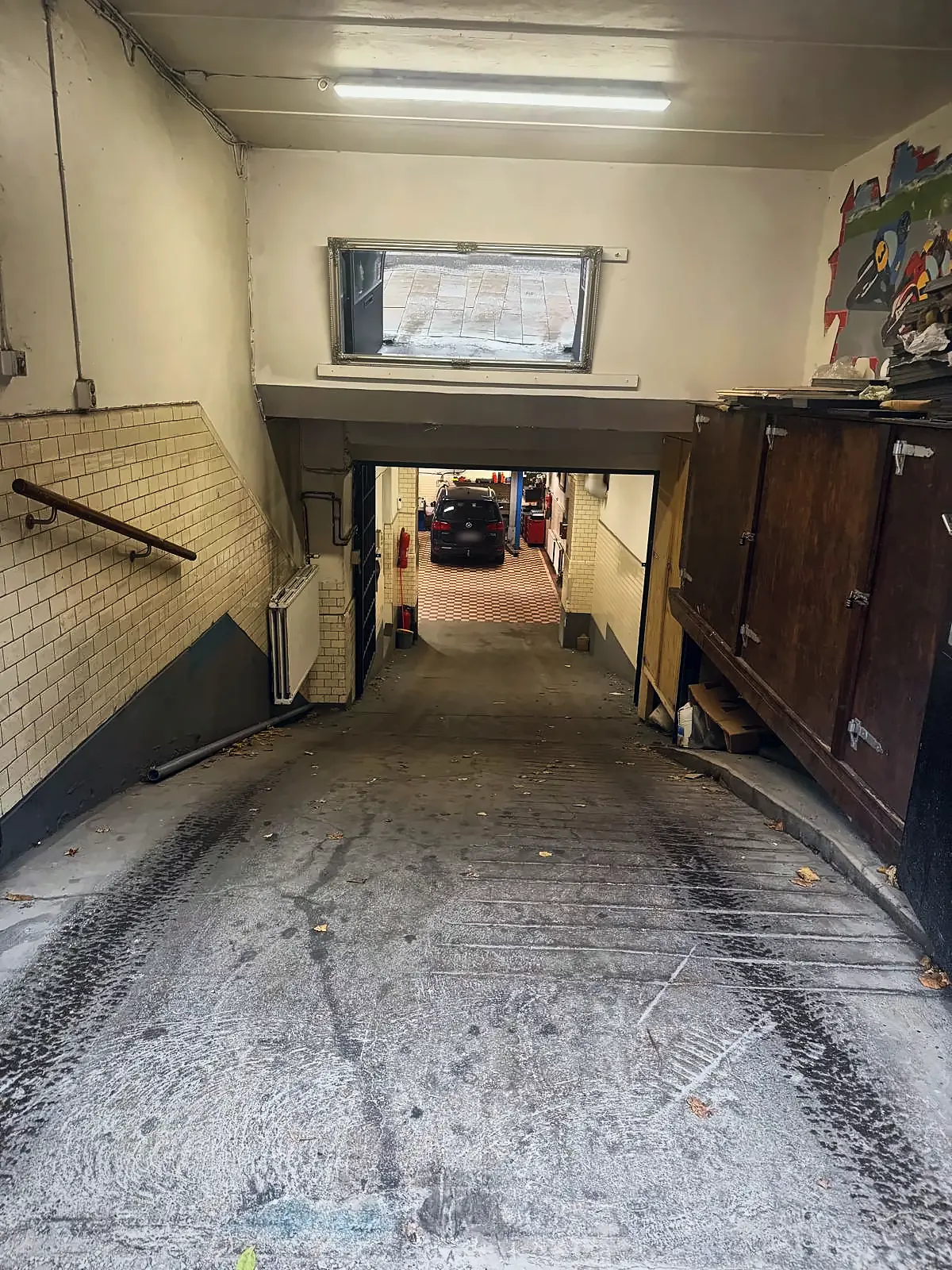 Nedfart från gatan till verkstaden med kaklade väggar och utsikt mot lyften längst in